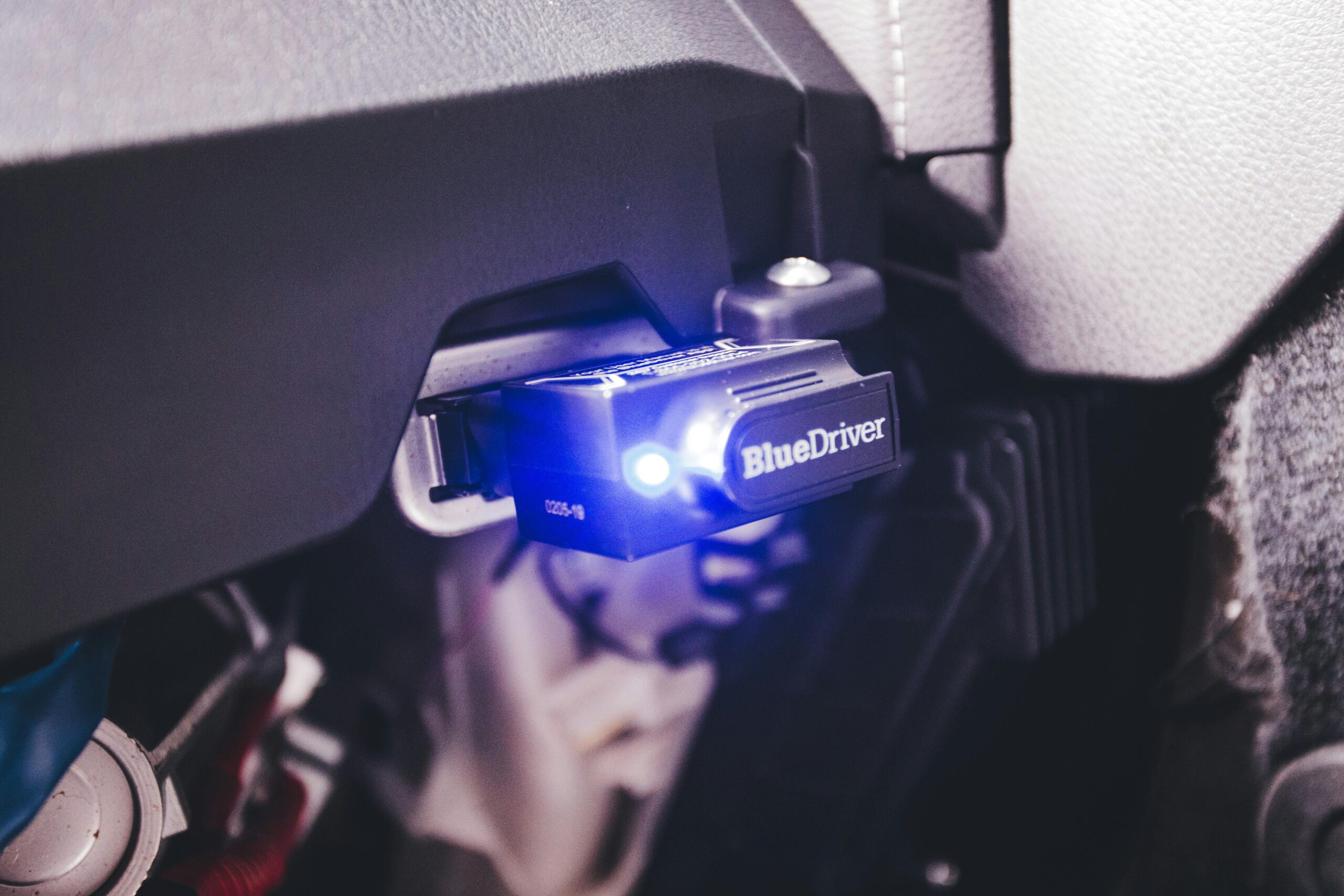 Close-up of a BlueDriver electronic car diagnostic tool plugged in a vehicle.
